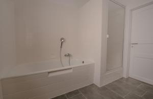 a white bathroom with a tub and a shower at Ferienwohnung Kassel mit Ladesäule & Balkon in Kassel