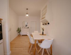 a white dining room with a table and white chairs at Ferienwohnung Kassel mit Ladesäule & Balkon in Kassel +6 photos