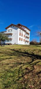 un grand bâtiment blanc sur une pelouse dans l'établissement Apartamento Urdaibai Busturia cerca de la playa, à Busturia