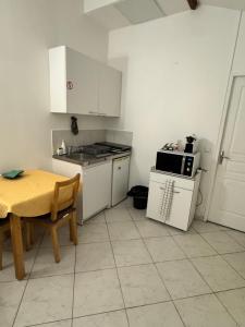 eine Küche mit einem Tisch, einem Herd und einer Mikrowelle in der Unterkunft Close to Paris & Disney in Le Perreux-sur-Marne