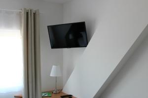 a flat screen tv hanging on a white wall at Hotel & Restaurant Zur Zwiebel in Peenemünde