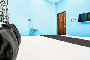 a bedroom with a bed with a blue wall at Hotel O Sai Sarkar Inn in Rāipur