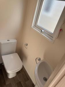 a bathroom with a toilet and a window and a sink at Camping Oasis Middelkerke Romy 1, 2, 3, 4 in Ostend +6 photos