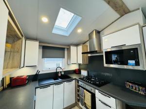 ヘイスティングスにあるEscape The City - Cozy Caravan Next To The Lakeの白いキャビネットと天窓付きのキッチン