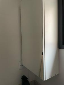 a white cabinet with a mirror in a room at Studio Central Todo Planejado com Ar Condicionado in Bagé