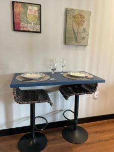 a blue table with two glasses and two chairs at Studio Central Todo Planejado com Ar Condicionado in Bagé