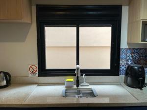 a kitchen sink with a window in a kitchen at Studio Central Todo Planejado com Ar Condicionado in Bagé