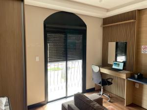a living room with a couch and a desk and a window at Studio Central Todo Planejado com Ar Condicionado in Bagé