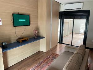 a living room with a couch and a flat screen tv at Studio Central Todo Planejado com Ar Condicionado in Bagé