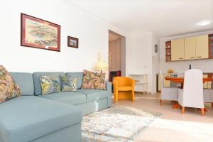 a living room with a blue couch and a kitchen at Seaview Apartment Bojan Rabac in Rabac