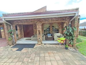 a brick house with a patio and a yellow chair at Simunye Retreat in White River