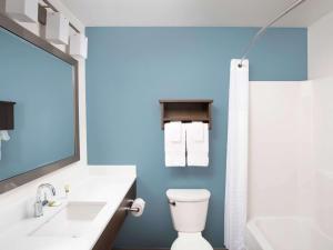 a bathroom with a white toilet and a blue wall at WoodSpring Suites Buford near Mall of Georgia-Lake Lanier in Buford +7 photos