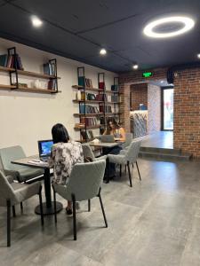 Due persone sedute ai tavoli con computer portatili in una stanza di Orion Hostel a Yerevan