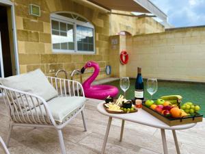 a table with a tray of fruit and a bottle of wine at Dar Leli Farmhouse in Xagħra