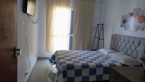 a bedroom with a bed with a blue and white quilt at Casa Balneário Arpoador in Peruíbe +29 photos