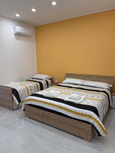 two beds in a room with yellow walls at Nicola's Apartments in Santa Maria La Carità +15 photos
