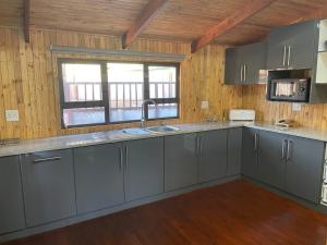 a kitchen with gray cabinets and a sink and a window at Shyalongubo dam cabin in Barberton