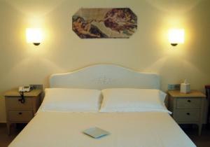 a bedroom with a white bed with a book on it at Hotel Piccolo Principe in Villongo SantʼAlessandro
