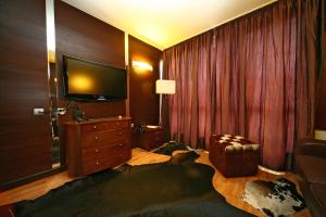 ein Hotelzimmer mit einem TV und einem Sofa sowie einem Zimmer in der Unterkunft Hotel City Pleven in Plewen