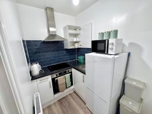 a small kitchen with a refrigerator and a microwave at Comfy Studio 30min to Central London in London