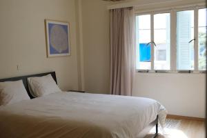 Un dormitorio con una cama blanca y una ventana. en Gladstone Apartment, en Nicosia
