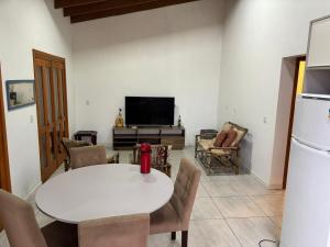 a living room with a white table and a tv at Casa Amarela com Vista para o Mar in Arroio do Sal