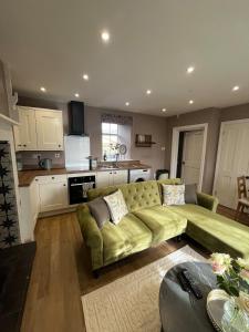 a living room with a green couch and a kitchen at Charlton Old Farm Guesthouse in Greenhaugh +23 photos