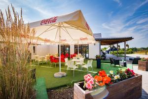 Eine Terrasse mit Tischen und Stühlen unter einem Coca-Cola-Sonnenschirm in der Unterkunft Pajda Mazur - Ośrodek wypoczynkowy in Stare Jabłonki