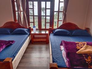 Dos camas en una habitación con ventana. en Tamang Valley Homestay, en Kalimpong