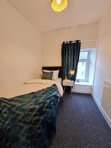 ein Schlafzimmer mit einem Bett und einem Fenster in der Unterkunft SleepyStays 3 Bedroom Modern & Central Location in Merthyr Tydfil
