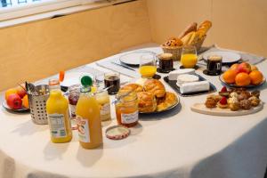 a table topped with breakfast foods and orange juice at Ômarais Guest House in Paris