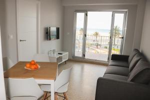 - un salon avec un canapé et une table avec des oranges dans l'établissement Primerísima Linea de Playa Gandía BONAIRE, à Puerto de Gandía