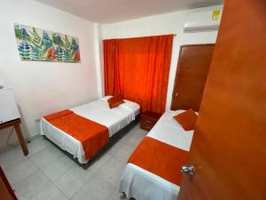 une chambre d'hôtel avec deux lits et un rideau rouge dans l'établissement Paraíso en Bocagrande habitaciones, à Carthagène des Indes 12 autres photos