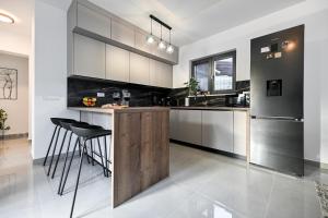 a kitchen with white cabinets and a bar with stools at Holiday home San Antonio in Bibinje