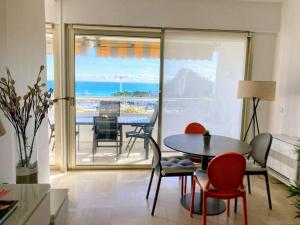 a living room with a table and chairs and a balcony at Appartement Moderne 4 Pers avec Clim et Parking, Villeneuve-Loubet Plage - FR-1-252A-36 in Villeneuve-Loubet