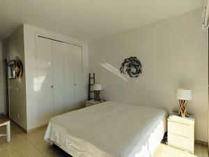 a white bedroom with a bed and two lamps at Appartement Moderne 4 Pers avec Clim et Parking, Villeneuve-Loubet Plage - FR-1-252A-36 in Villeneuve-Loubet