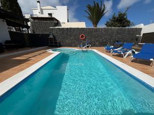 basen z niebieskimi krzesłami i dom w obiekcie Villa Adel 56, private heated pool, parking w mieście Playa Blanca