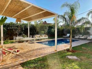 a pavilion with a table and chairs next to a pool at Villa Ambre with Pool And Garden in El Aggada