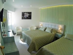 a hotel room with two beds and a table at VILA FORMOSA AL-Estabelecimento de Hospedagem,Quartos-Rooms in Monte Gordo