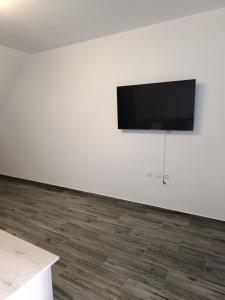 Un televisor de pantalla plana en una pared blanca en Haraki Blue Houses, en Charaki