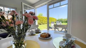 a table with a vase of flowers and a vase of cake at Haus Eversand Nr 2 in Cuxhaven