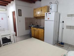 a kitchen with a white refrigerator and wooden cabinets at Los Colibríes in San José +3 photos