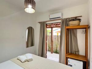 a bedroom with a bed and a mirror and a window at Hospedaria Vale Maion in Caraíva