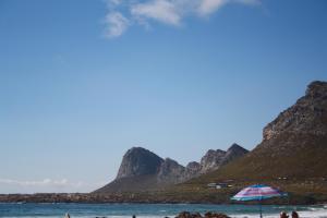 a group of people on a beach with an umbrella at Happy's Hood in Pringle Bay