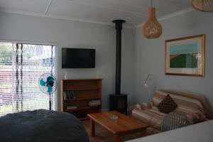 a living room with a couch and a tv at Happy's Hood in Pringle Bay