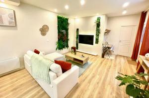 a living room with a white couch and a tv at L'atelier vert - SPA, Suite Luxe, Proche Hypercentre - Classé 4 étoiles in Troyes