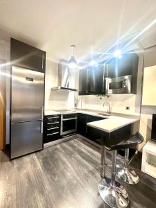 Una cocina con frigorífico de acero inoxidable y fregadero. en Apartamento El Sol, en Cervera de Pisuerga