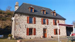 an old stone house with red shuttered windows at Les Nuits de Vieillespeze in Saint-Projet-de-Salers