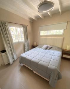 a bedroom with a large white bed and two windows at Casa Libertad in Mar de las Pampas
