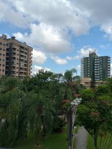 a park with palm trees and buildings in a city at Vila Caiçara 80 metros da praia in Praia Grande
